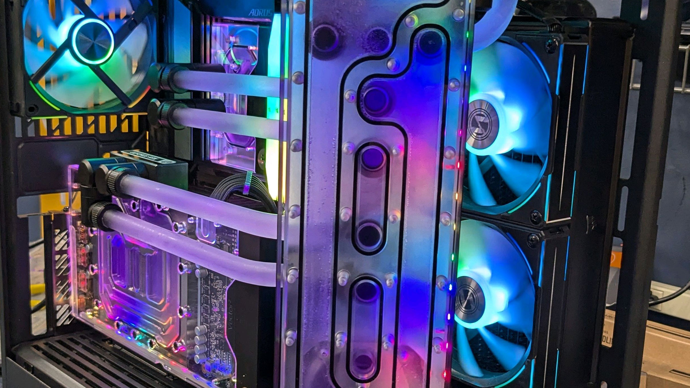 Interior view of a custom-built PC with multiple cooling fans with multi-colored lights, neatly organized cables, and liquid cooling pipes